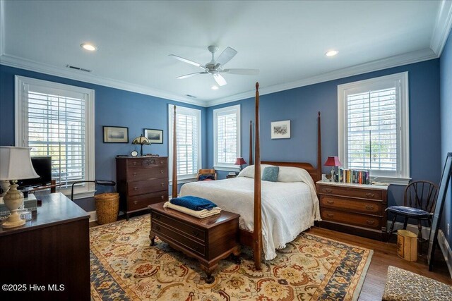 bedroom featuring visible vents, a ceiling fan, wood finished floors, and crown molding