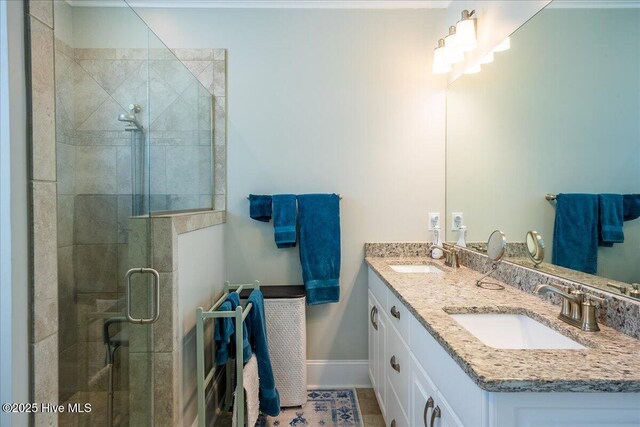 full bath with double vanity, baseboards, a stall shower, and a sink