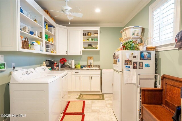 washroom featuring ornamental molding, a ceiling fan, washer and clothes dryer, a sink, and cabinet space