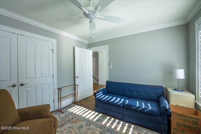 living area with ceiling fan, baseboards, wood finished floors, and ornamental molding