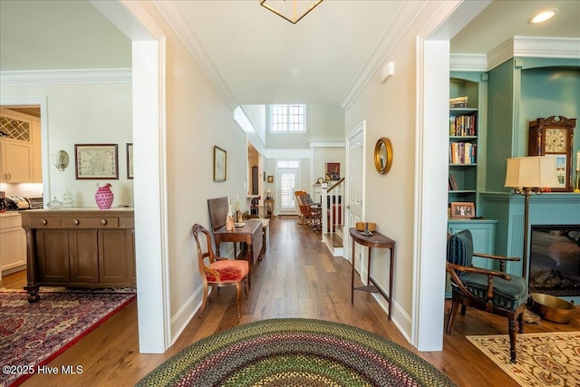 hallway featuring built in shelves, baseboards, wood finished floors, and ornamental molding