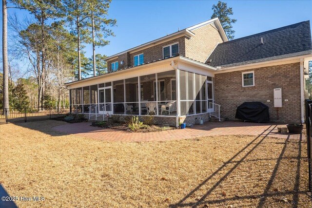 back of property with a patio, fence, brick siding, and a sunroom