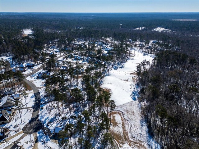 snowy aerial view with a wooded view