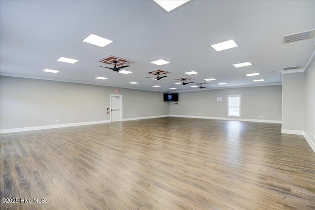 spare room featuring visible vents, baseboards, wood finished floors, and crown molding