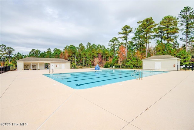 community pool featuring an outdoor structure, a patio area, and fence