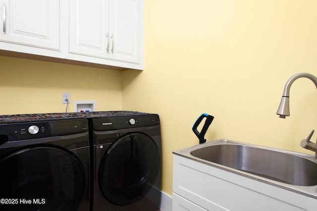 clothes washing area with washer and dryer, cabinets, and sink