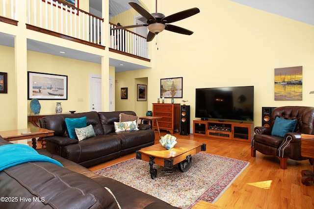 living room featuring light hardwood / wood-style floors, a high ceiling, and ceiling fan