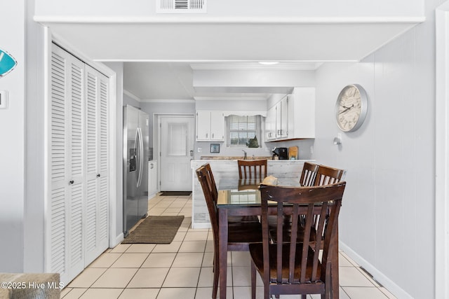 tiled dining room featuring ornamental molding and sink