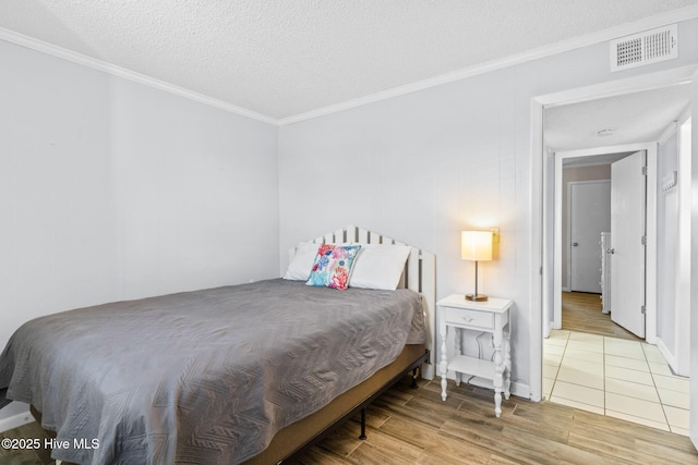 bedroom with a textured ceiling, light hardwood / wood-style floors, and crown molding