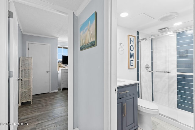 bathroom featuring vanity, a shower with door, crown molding, toilet, and a textured ceiling