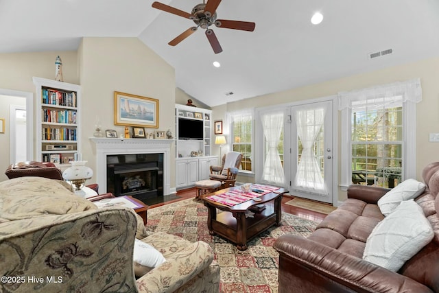 living room with built in shelves, wood-type flooring, and plenty of natural light