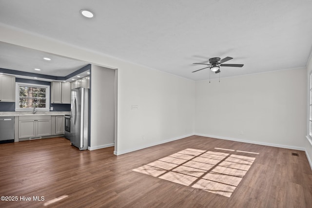 unfurnished living room with ceiling fan, wood-type flooring, and sink