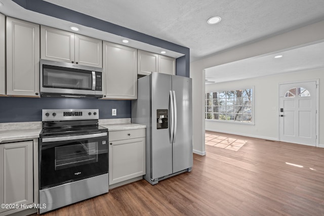 kitchen with a textured ceiling, gray cabinets, stainless steel appliances, and hardwood / wood-style flooring