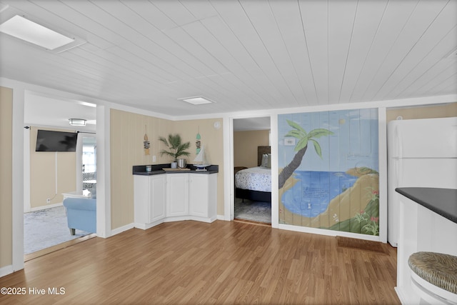 bedroom with ensuite bathroom, light hardwood / wood-style flooring, white fridge, and wood ceiling