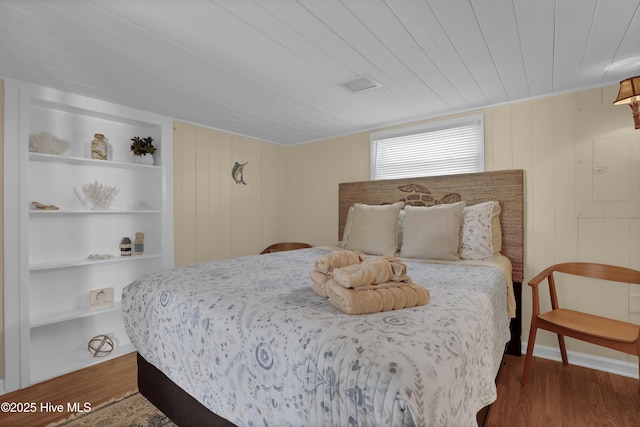 bedroom featuring wood ceiling, wood walls, and wood-type flooring