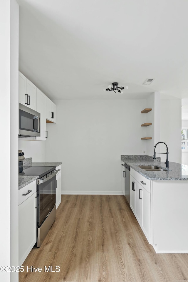 kitchen with sink, light hardwood / wood-style flooring, light stone counters, white cabinetry, and stainless steel appliances