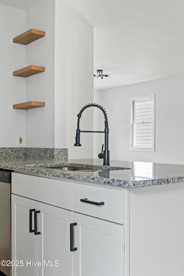 kitchen with white cabinets, light stone countertops, dishwasher, and sink