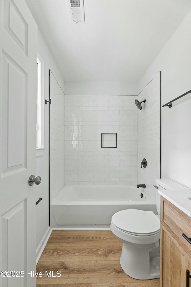 full bathroom with hardwood / wood-style floors, vanity, toilet, and tiled shower / bath