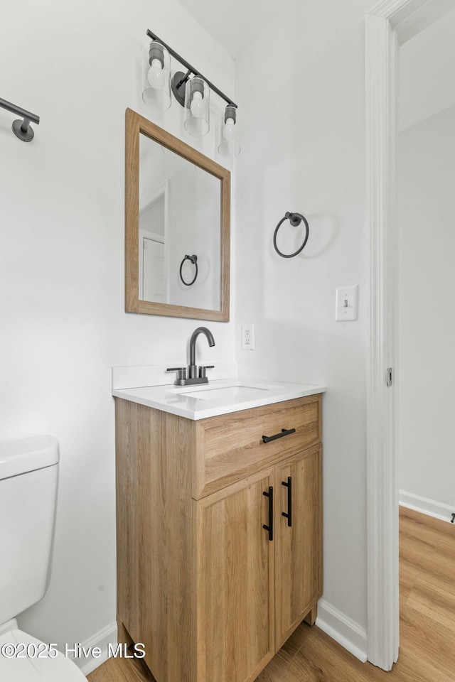 bathroom featuring wood-type flooring, vanity, and toilet