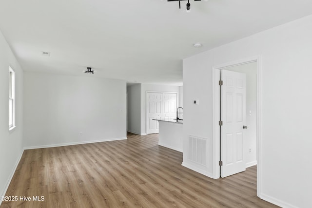 unfurnished living room with light wood-type flooring and sink