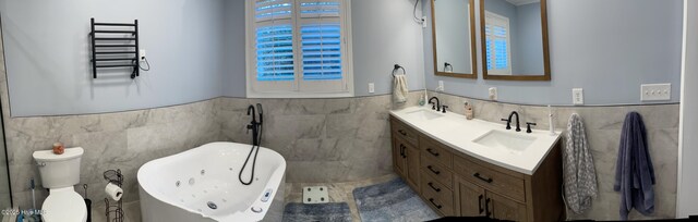 bathroom with tile walls, a tub to relax in, vanity, and toilet