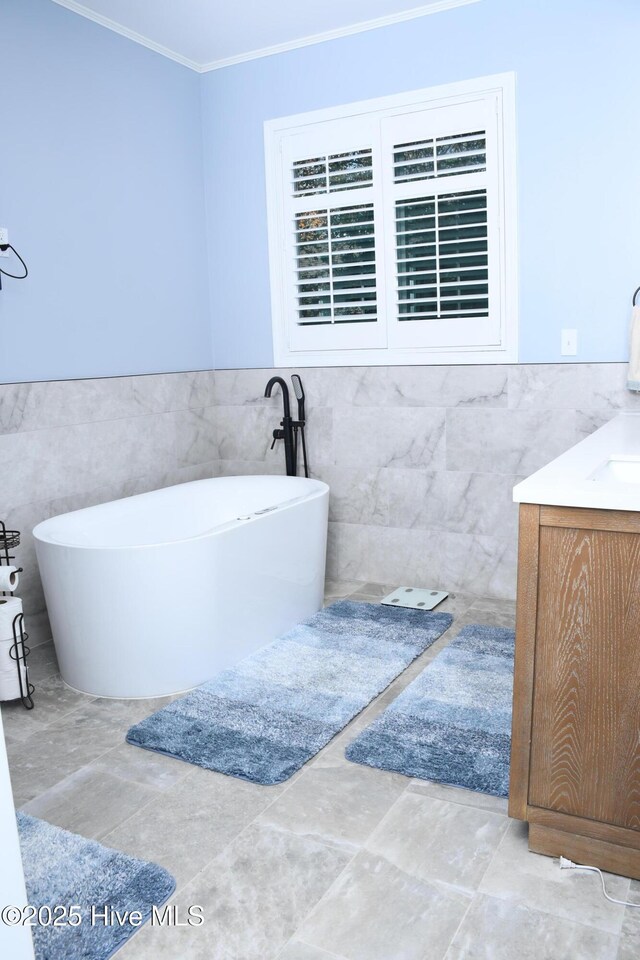 bathroom featuring vanity, tile walls, tile patterned floors, a tub, and crown molding