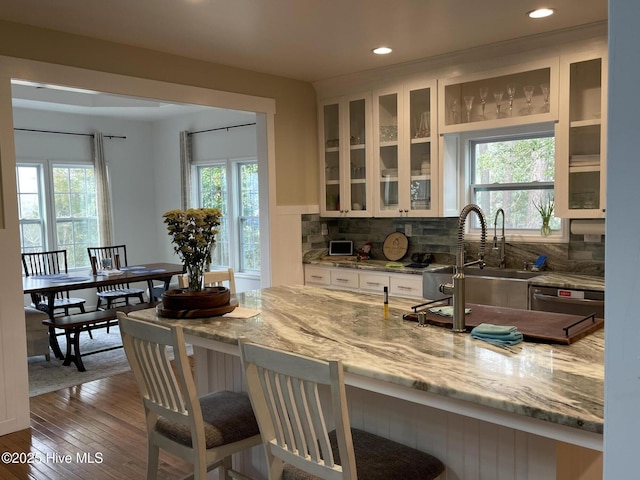 kitchen with white cabinetry, a breakfast bar area, light stone countertops, and tasteful backsplash