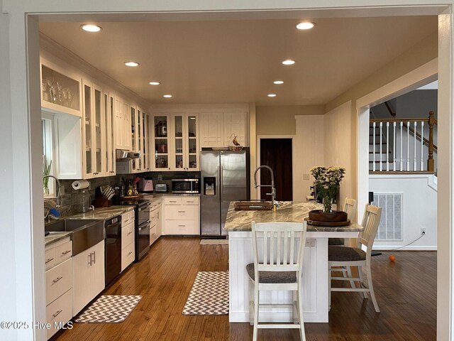 kitchen with backsplash, dishwasher, sink, white cabinets, and stone countertops