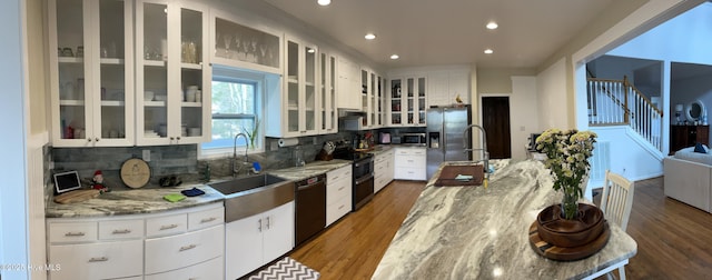 kitchen with white cabinetry, appliances with stainless steel finishes, sink, and light stone counters