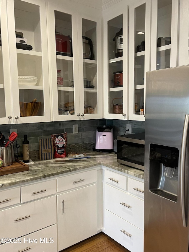 kitchen featuring appliances with stainless steel finishes, dark hardwood / wood-style floors, white cabinets, decorative backsplash, and light stone countertops