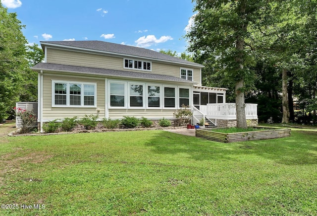 rear view of house featuring a sunroom and a lawn