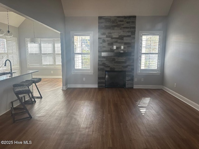 unfurnished living room featuring a fireplace, a healthy amount of sunlight, lofted ceiling, and sink