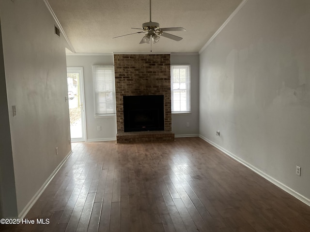 unfurnished living room featuring hardwood / wood-style floors, ceiling fan, crown molding, and a brick fireplace