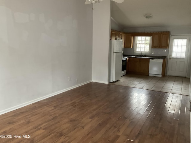 kitchen with light wood-type flooring, white appliances, vaulted ceiling, ceiling fan, and sink