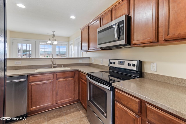 kitchen featuring pendant lighting, sink, stainless steel appliances, a notable chandelier, and light tile patterned flooring