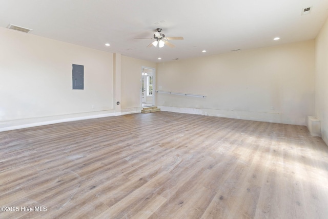 spare room with ceiling fan, electric panel, and light hardwood / wood-style flooring