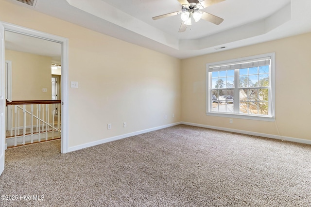 unfurnished room with ceiling fan, a tray ceiling, and carpet