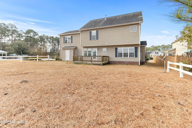 back of property featuring a wooden deck and a yard