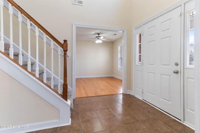 foyer entrance with ceiling fan and dark tile patterned flooring