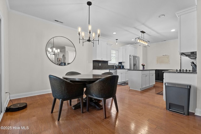 dining space with crown molding, wood-type flooring, and an inviting chandelier