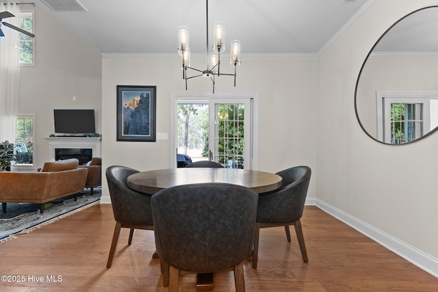 dining space with wood-type flooring, ornamental molding, and a notable chandelier