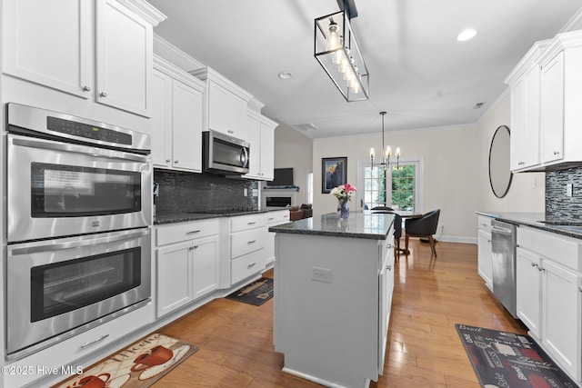 kitchen featuring white cabinets, a center island, stainless steel appliances, and hanging light fixtures