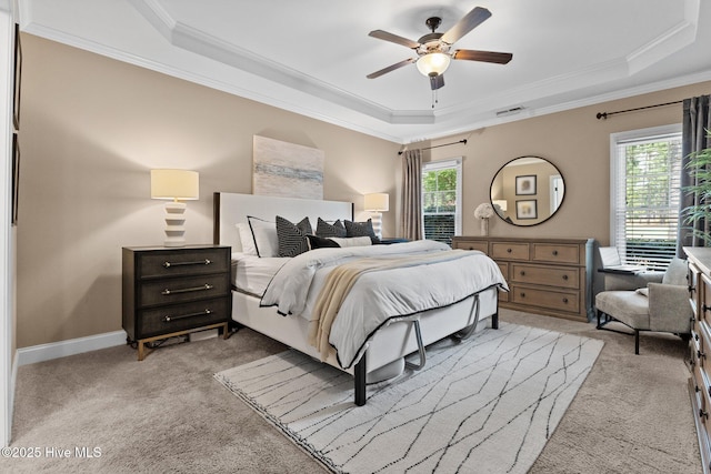 carpeted bedroom with ceiling fan, crown molding, and a tray ceiling