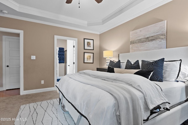 carpeted bedroom featuring ensuite bath, a raised ceiling, ceiling fan, and crown molding