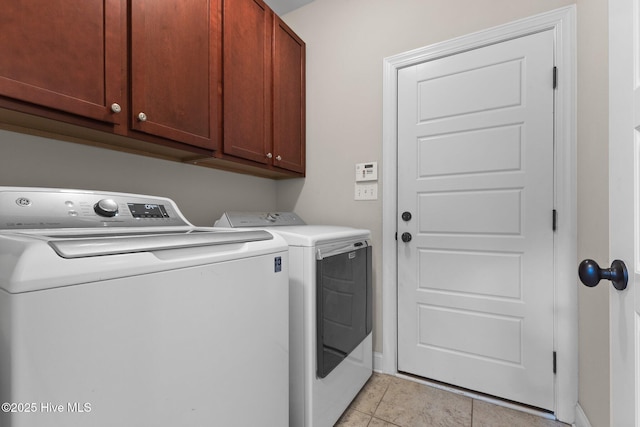 clothes washing area with cabinets, light tile patterned floors, and washing machine and dryer