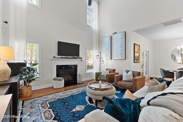 living room featuring hardwood / wood-style floors, a towering ceiling, and crown molding