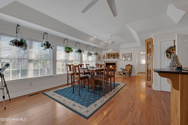 dining room with ceiling fan, hardwood / wood-style floors, and a raised ceiling