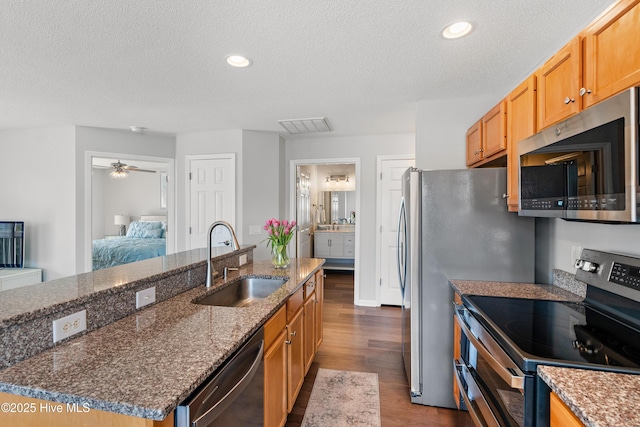 3350 Club Villas Dr Unit 205, Southport, NC 28461 - kitchen with stainless steel appliances, a sink, dark wood-style floors, a textured ceiling, and a kitchen island with sink