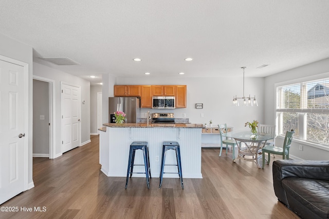 3350 Club Villas Dr Unit 205, Southport, NC 28461 - kitchen featuring stainless steel appliances, wood finished floors, a chandelier, a breakfast bar, and recessed lighting