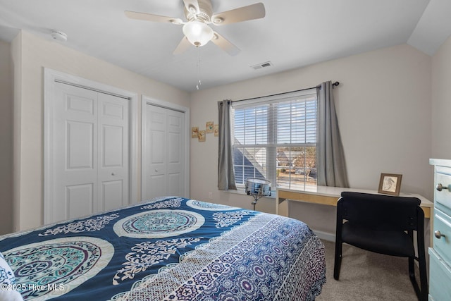 carpeted bedroom featuring ceiling fan and multiple closets